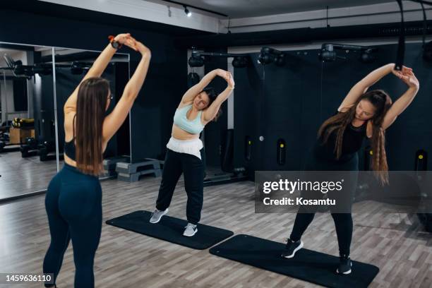 personal training for two plus size women led by a personal trainer in the gym - obesity trainer stock pictures, royalty-free photos & images