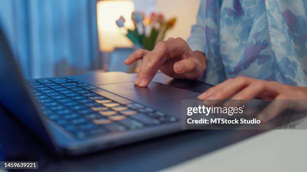 closeup young muslim woman sit on bed with computer laptop and on folding laptop table, portable holder stand hold paperwork and think create on work idea in bedroom at night. work from home. - islamic finance stock pictures, royalty-free photos & images