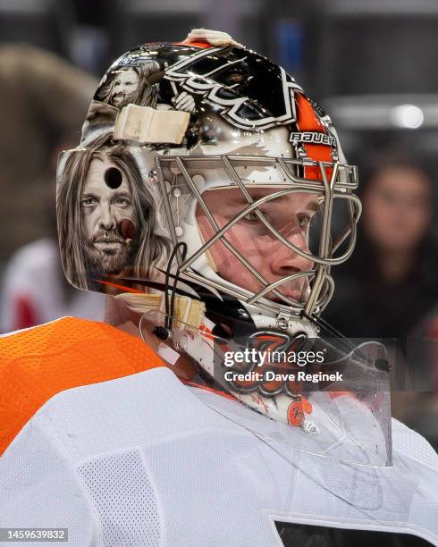 Carter Hart of the Philadelphia Flyers looks down the ice wearing his Foo Fighters band theme mask showing the late drummer Taylor Hawkins on the...