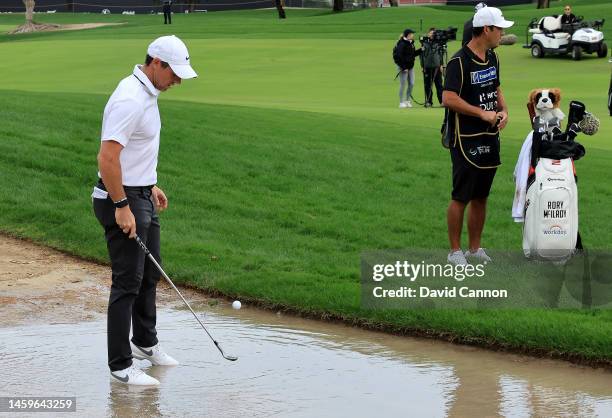 Rory McIlroy of Northern Ireland retrieves his ball from a puddle beside the fairway before he plays his second shot on the 10th hole during Day One...