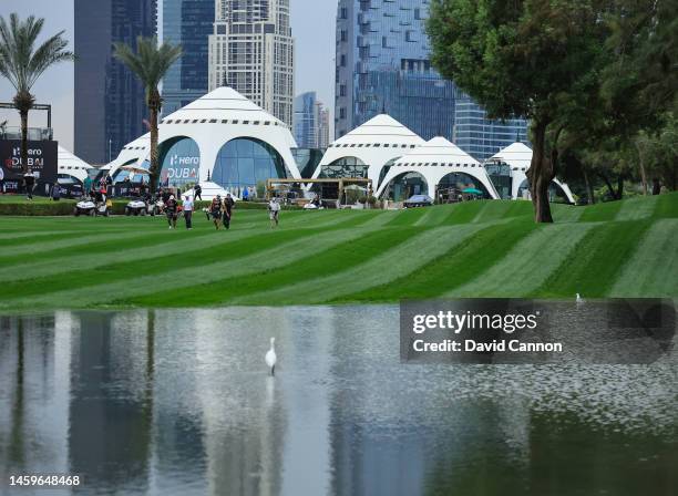 Rory McIlroy of Northern Ireland, Tommy Fleetwod of Engalnd and Ryan Fox of New Zealand walk down the first fairway past a huge puddle left over from...