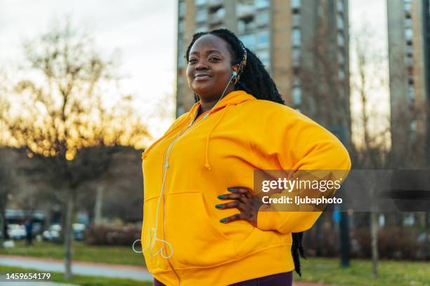 porträt einer lächelnden frau in der stadtstraße nach dem laufen. - images of fat black women stock-fotos und bilder