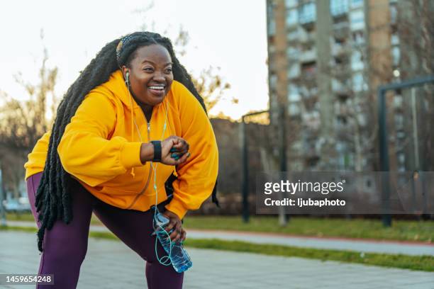 young plus size woman using her smart watch before running outdoors. - morbidly obese woman 個照片及圖片檔
