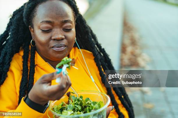 giovane sportiva felice che mangia insalata sana durante una pausa - grasso nutrienti foto e immagini stock