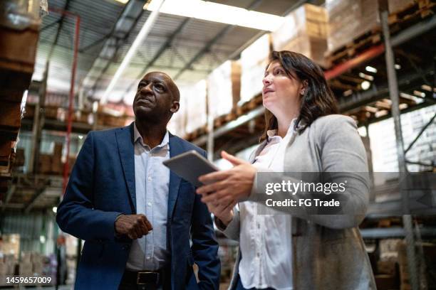 coworkers talking while walking in a warehouse - a meeting place for the european digital industry stock pictures, royalty-free photos & images