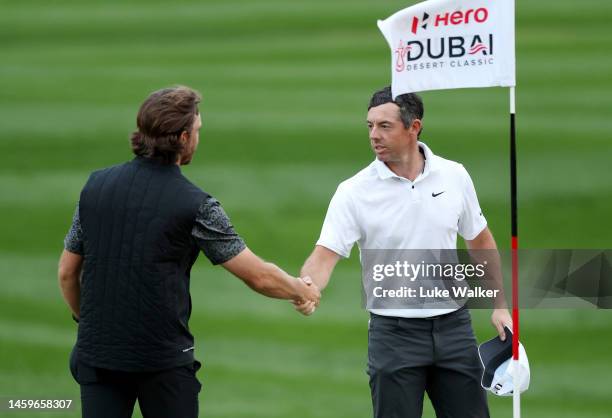 Tommy Fleetwood of England and Rory McIlroy of Northern Ireland shake hands on the 7th green as play is suspended during Day One of the Hero Dubai...
