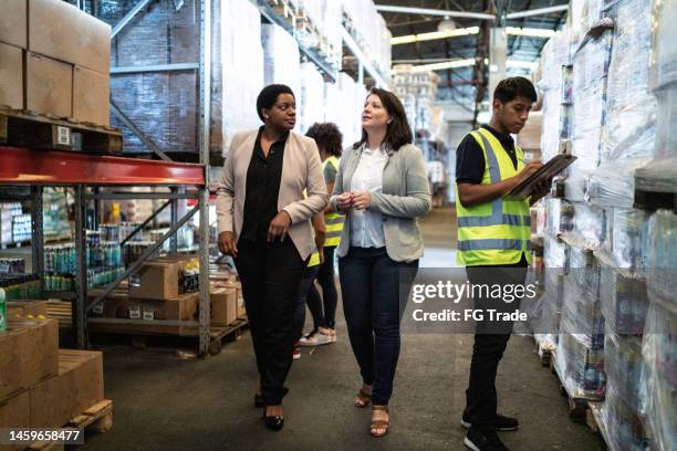 coworkers talking while walking in a warehouse - grocery delivery stock pictures, royalty-free photos & images