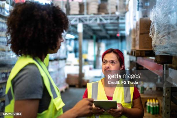 disabled young woman working with coworker in a warehouse - sayings stockfoto's en -beelden