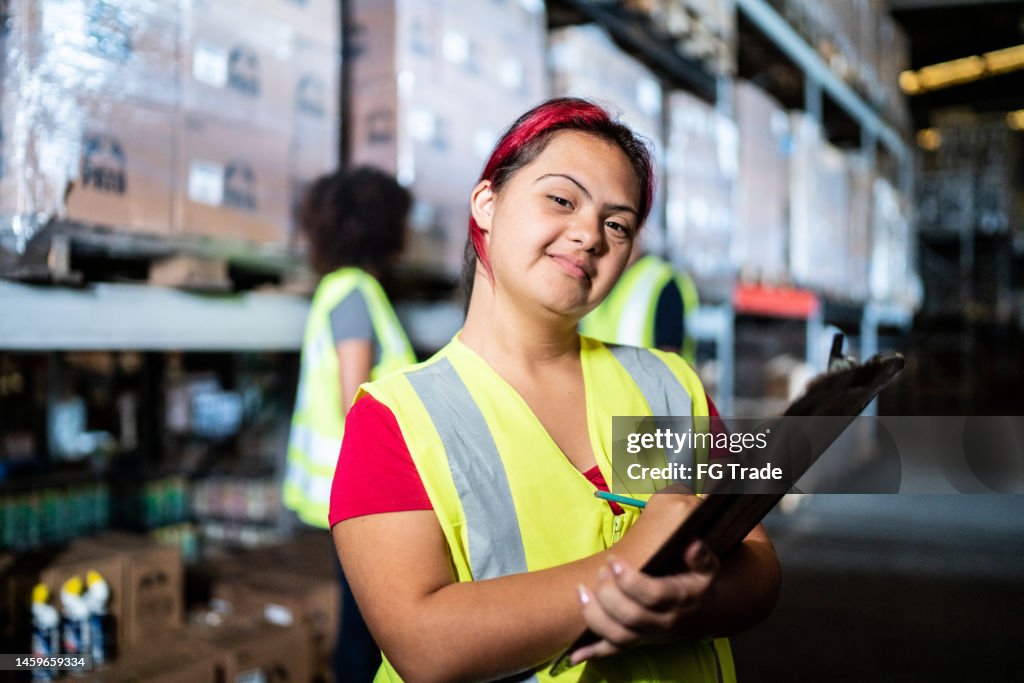Portrait of a disabled young woman holding a clipboard in a warehouse