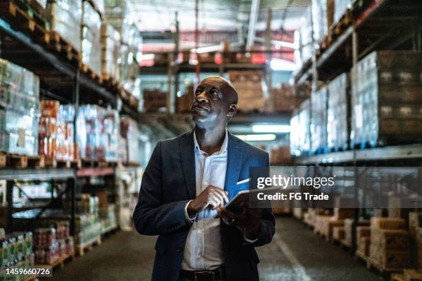 hombre maduro usando la tableta digital en un almacén - business owner suit fotografías e imágenes de stock