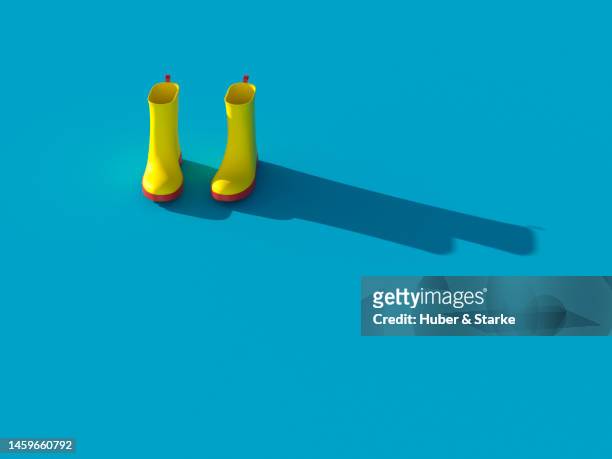 yellow rubber boots with shadow on blue background - yellow boot stock pictures, royalty-free photos & images