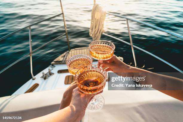 a close-up shot of friends clinking sparkling wine glasses at sunset on a yacht - comemoração evento imagens e fotografias de stock