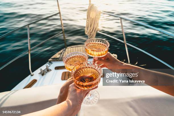 a close-up shot of friends clinking sparkling wine glasses at sunset on a yacht - båtar och fartyg bildbanksfoton och bilder