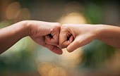 Fist bump, friends and hands together for welcome with support, diversity and partnership collaboration. Bokeh background, racism and friendship goal welcome greeting collaboration outdoor with bokeh