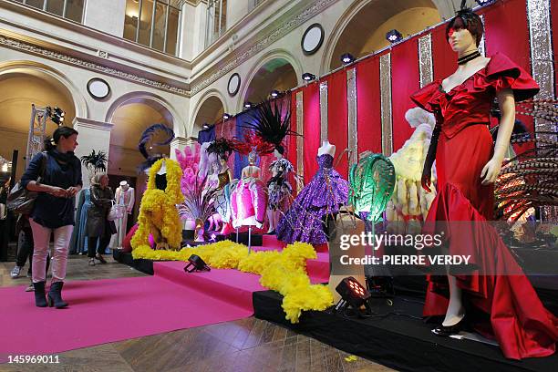 People look at costumes from the Folies Bergere displayed at the Palais de la Bourse as part of the "Ventes de folie" auction in Paris on June 8,...