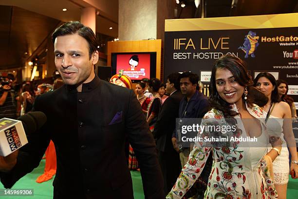 Indian actor Vivek Oberoi speaks to the media accompanied by his wife on the green carpet during the IIFA Rocks Green Carpet on day two of the 2012...