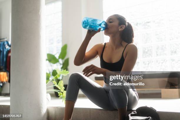 femme latine buvant de l’eau au gymnase à partir d’une bouteille - coach bus photos et images de collection