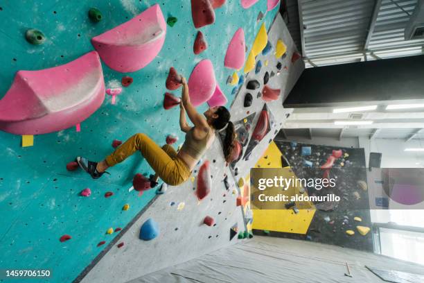 female climber climbing in indoor gym - bouldering stock pictures, royalty-free photos & images