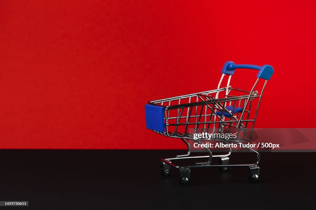 Close-up of shopping cart against red background