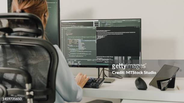gros plan de jeunes développeuses de logiciels asiatiques utilisant un ordinateur pour écrire du code assises à un bureau avec plusieurs écrans travaillant à distance à la maison. - java stock photos et images de collection