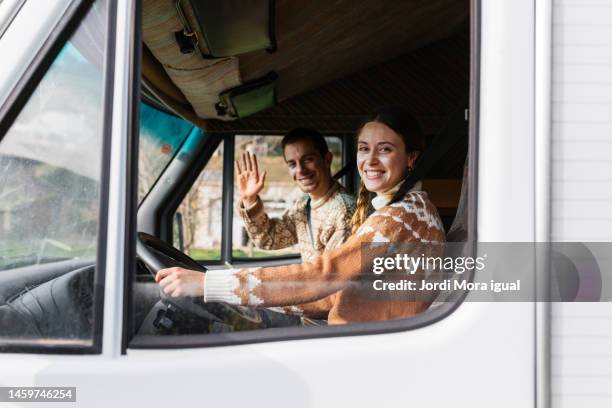 alternative couple waving while driving a caravan - white van profile stock pictures, royalty-free photos & images