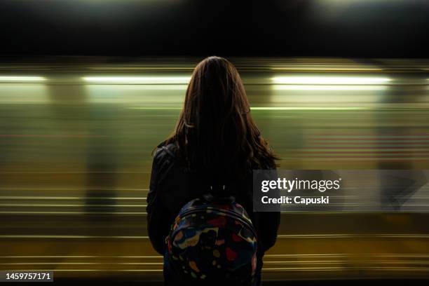 donna che guarda il passaggio della metropolitana - binario di stazione ferroviaria foto e immagini stock