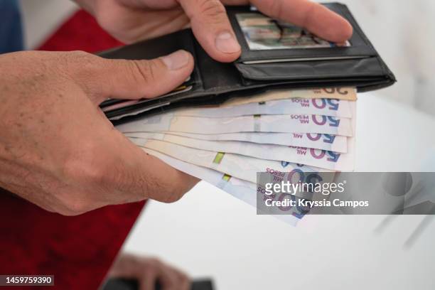 man's hands holding wallet and colombian pesos bills - seleccion colombia stock-fotos und bilder