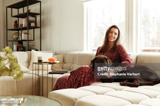woman smiling on the couch - pets thunderstorm stock pictures, royalty-free photos & images