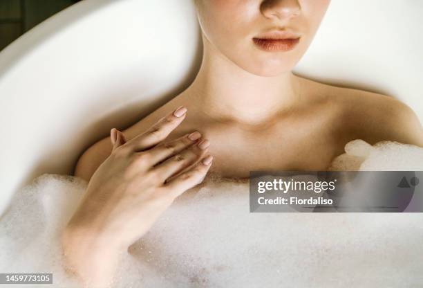 washing massage glove with shower foam for washing the body in female hands. relaxation and beauty treatments. natural beauty, daily skincare routine. moisturizing, cleansing - sleutelbeen stockfoto's en -beelden