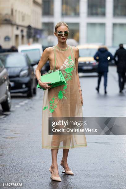 Leonie Hanne wears green sunglasses, green bag, brown dress with green floral print, heels outside Fendi during Paris Fashion Week - Haute Couture...