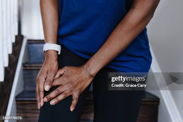 woman grabs her leg while descending stairs - muscle cramps stock pictures, royalty-free photos & images