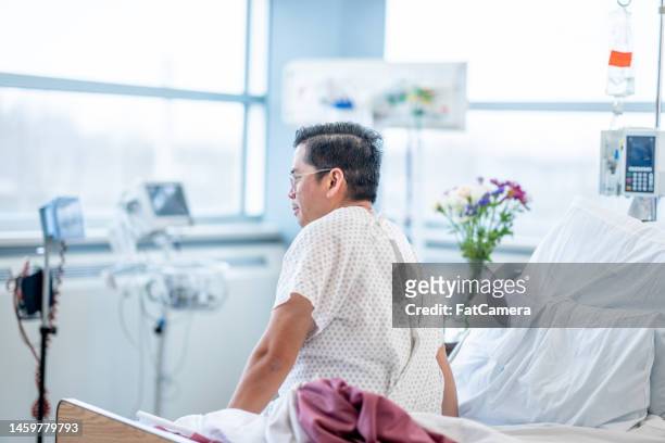 patient siting up over the edge of the bed - injured man in hospital bed stockfoto's en -beelden