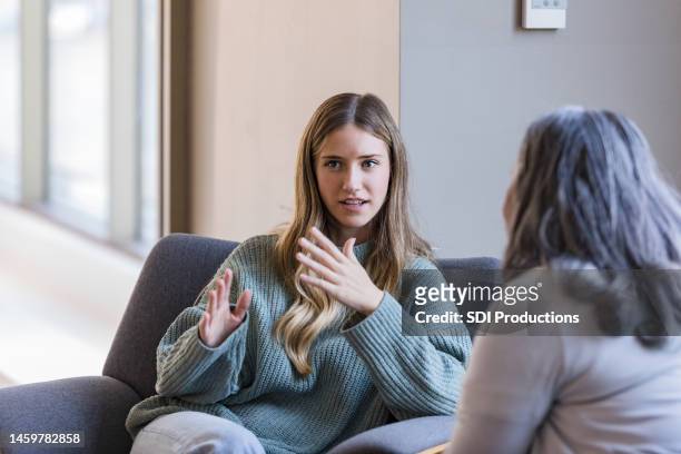 young adult university student talks with her peer - psychotherapy imagens e fotografias de stock