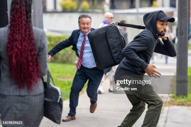 mid adult businessman running for african american thief at city sidewalk - mugger stock pictures, royalty-free photos & images