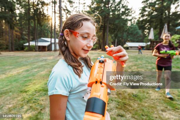 tween girls having playful nerf gun battle outside - toy gun stock pictures, royalty-free photos & images