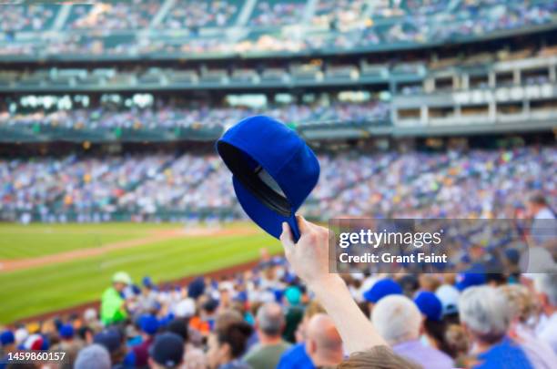 man holding up baseball cap. - baseball crowd stock-fotos und bilder