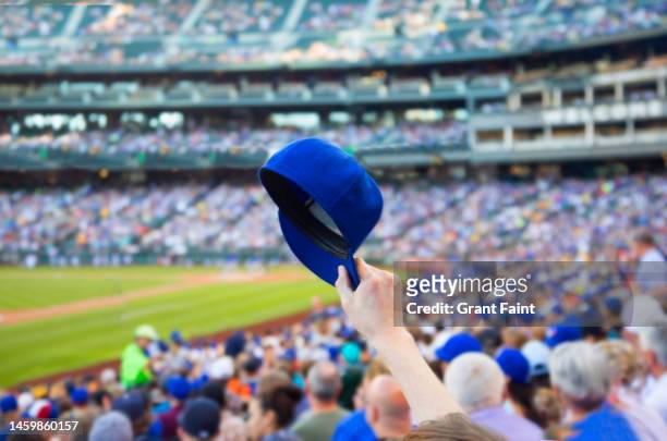 man holding up baseball cap. - baseball stockfoto's en -beelden