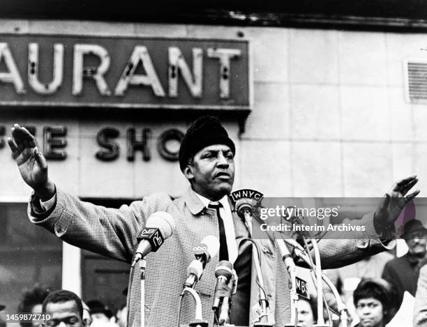 African American civil rights activist Bayard Rustin raises his hands as he speaks into a microphone while addressing a crowd, New York City, New...