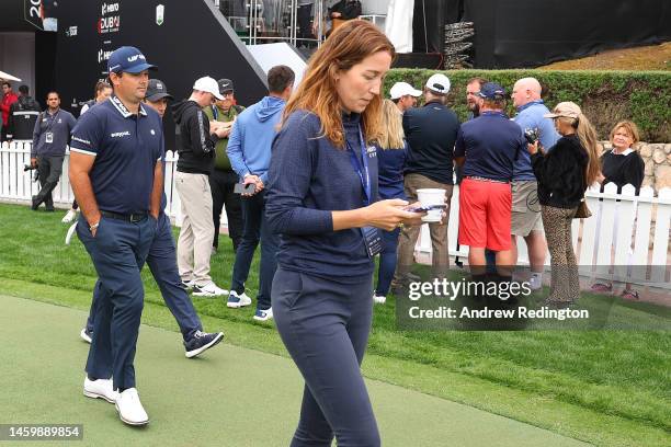 Patrick Reed of The United States walks onto the practice putting green past Rory McIlroy of Northern Ireland whilst they are interviewed by the...