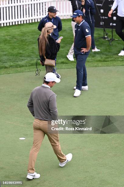 Rory McIlroy of Northern Ireland walks past Patrick Reed of The United States on the practice putting green on Day Two the Hero Dubai Desert Classic...