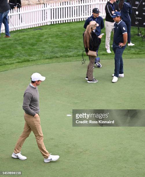 Rory McIlroy of Northern Ireland walks past Patrick Reed of The United States on the practice putting green on Day Two the Hero Dubai Desert Classic...