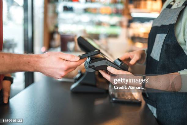 caucasian male paying with smartphone in a cafe - pos stock pictures, royalty-free photos & images