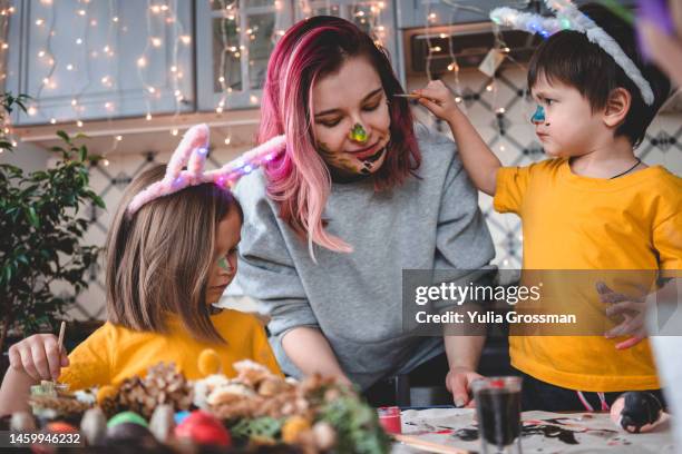 happy easter! a little boy and a girl in bunny ears with pink-hair mama paint eggs for easter together at home. close-up. - happy easter mom stockfoto's en -beelden