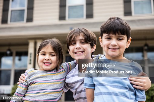 Portrait of siblings in front of suburban home