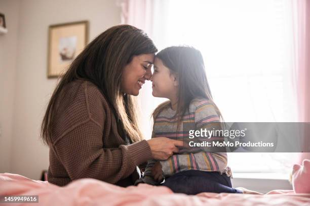 mother and daughter cuddling on her bed - family hugging bright stock pictures, royalty-free photos & images