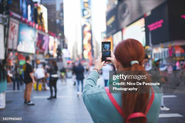 tourist taking pictures at time square, new york city, usa - american influencer - fotografias e filmes do acervo