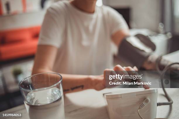 a mature woman measures blood pressure on a digital meter - hypertensive stock pictures, royalty-free photos & images