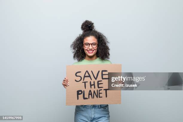 portrait of a female young activist holding a poster - afro caribbean portrait stock pictures, royalty-free photos & images