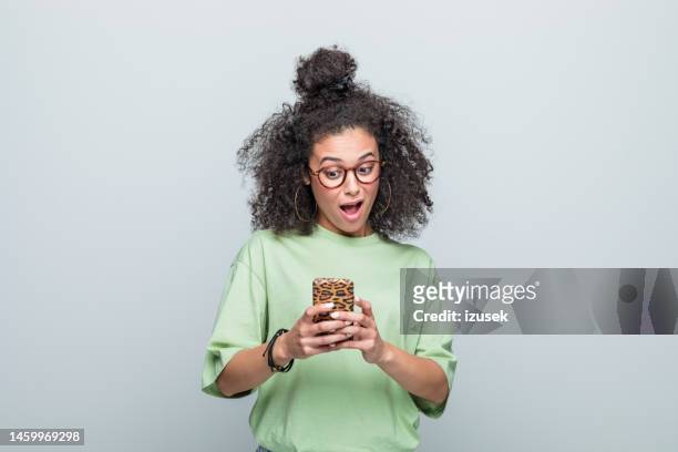 電話を使う驚いた若い女性のポートレート - サプライズ ストックフォトと画像