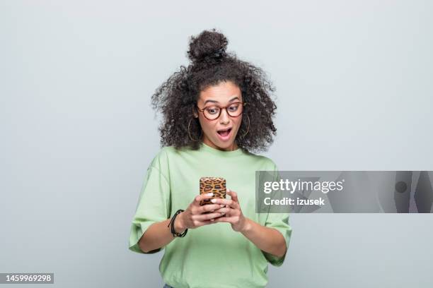 portrait of surprised young woman using phone - disbelief 個照片及圖片檔